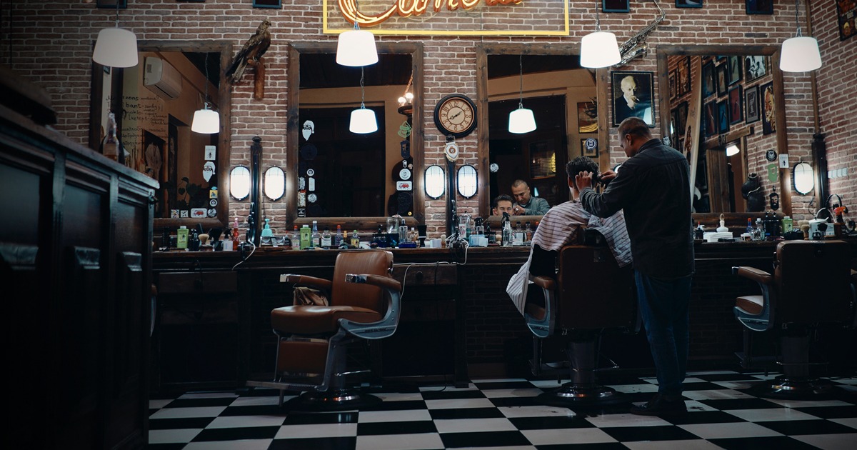 dimly lit barbershop with one barber and customer