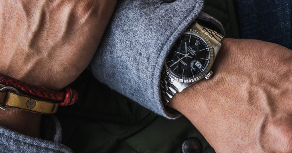 steel rolex datejust with black dial and grey shirt closeup