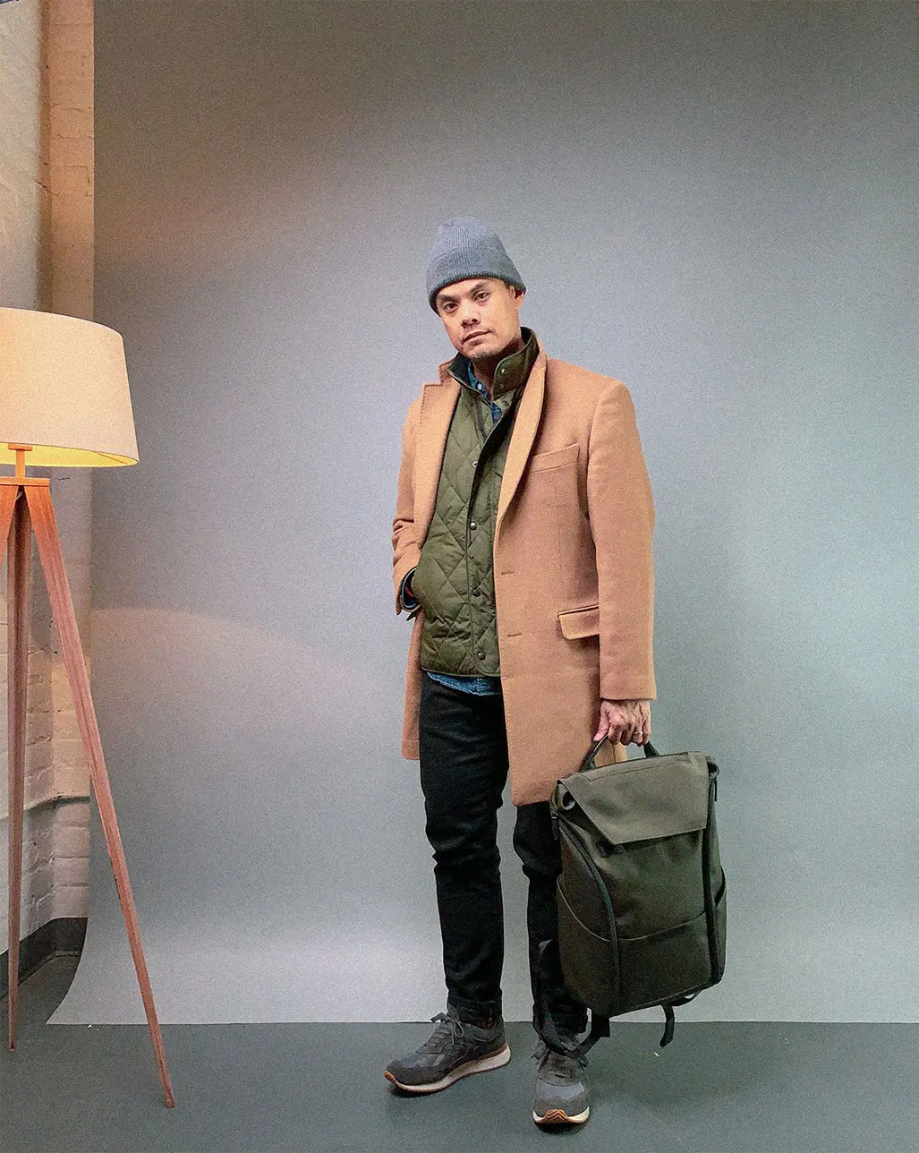 man in tan overcoat green quilted vest and grey beanie