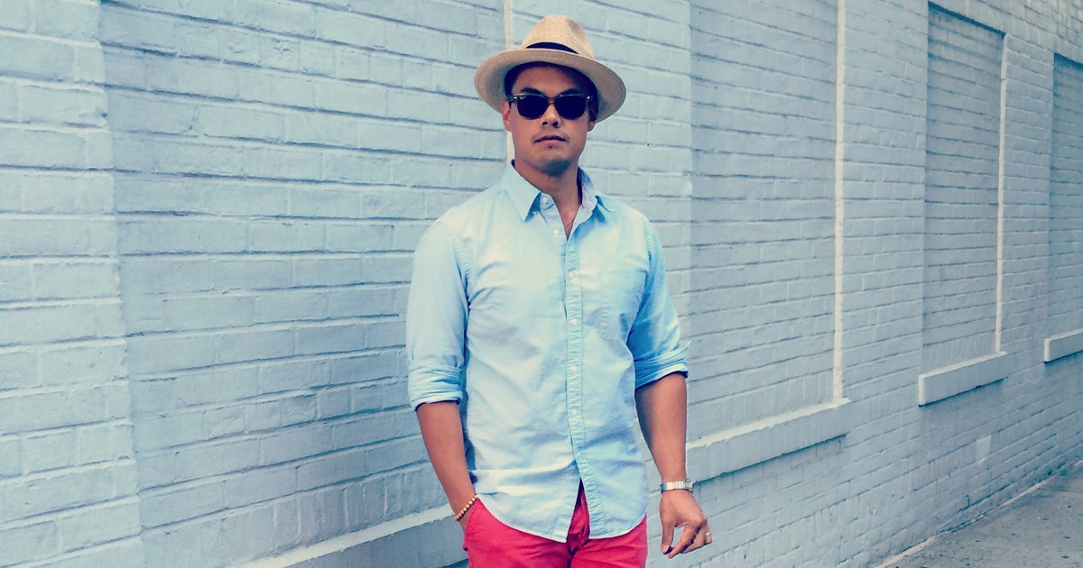 cropped photo of man wearing blue oxford shirt with red shorts and panama hat