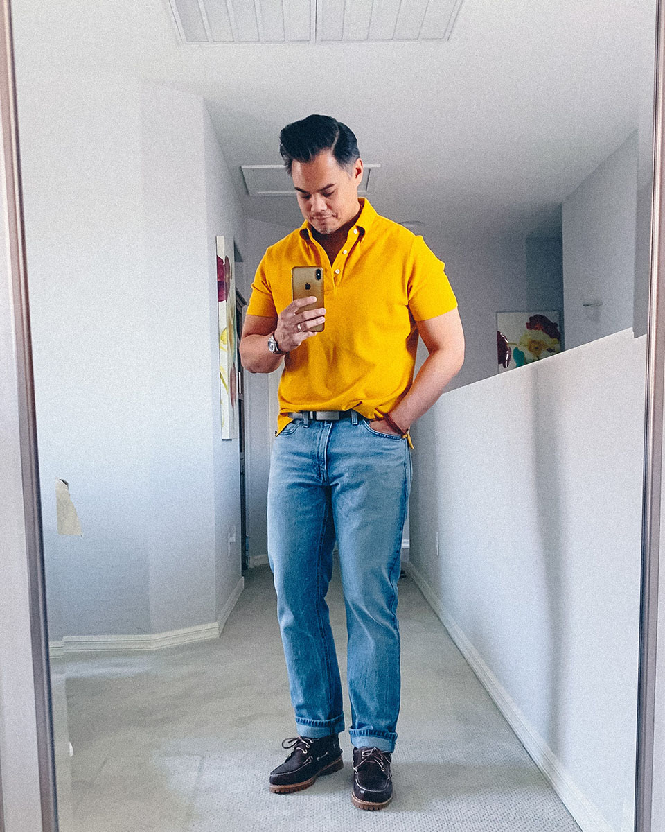 asian man wearing light blue jeans and a yellow polo