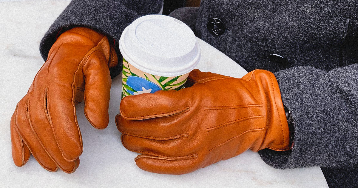 man wearing leather gloves holding coffee