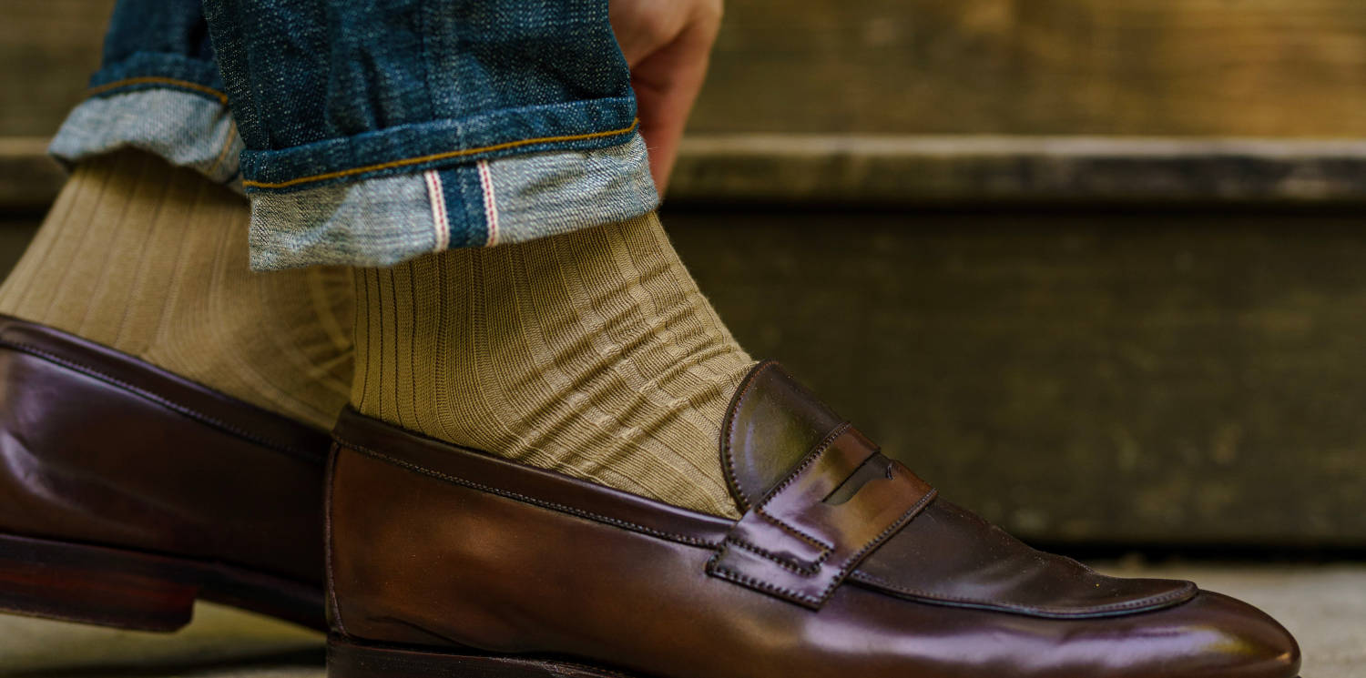 closeup of selvedge jeans cuff tan socks from Boardroom Socks and brown loafers