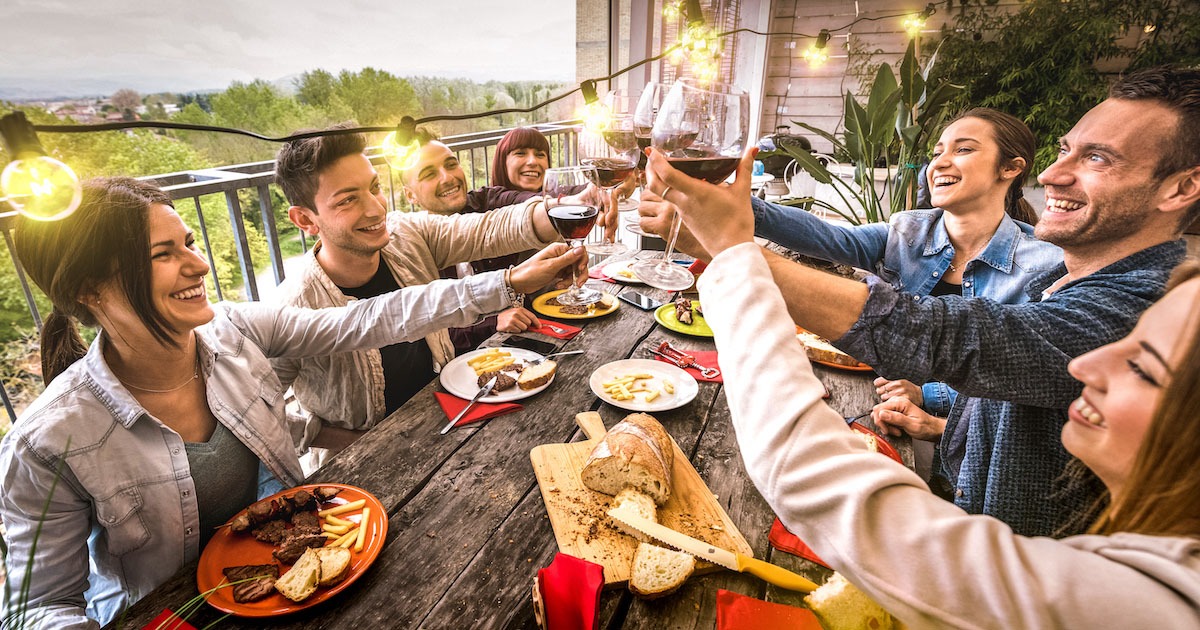 group of friends around table toasting and eating