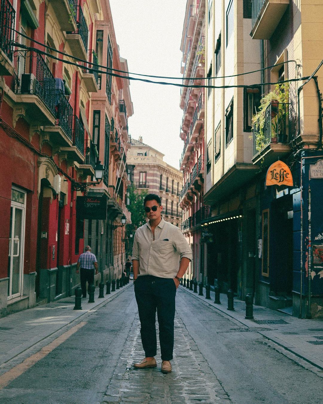 men's summer pants in navy and a khaki oxford lightweight button down worn by a man standing in the middle of an empty street